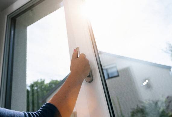 A man reaching to open a conservatory door glass